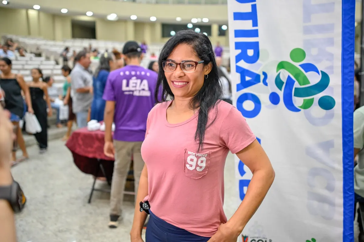 Voluntária ao lado do banner do Mutirão ACB